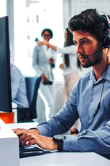 Un homme concentré portant un casque tout en travaillant sur un ordinateur.